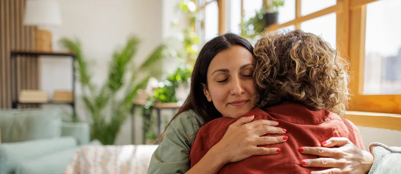Two women sharing a comforting embrace at home